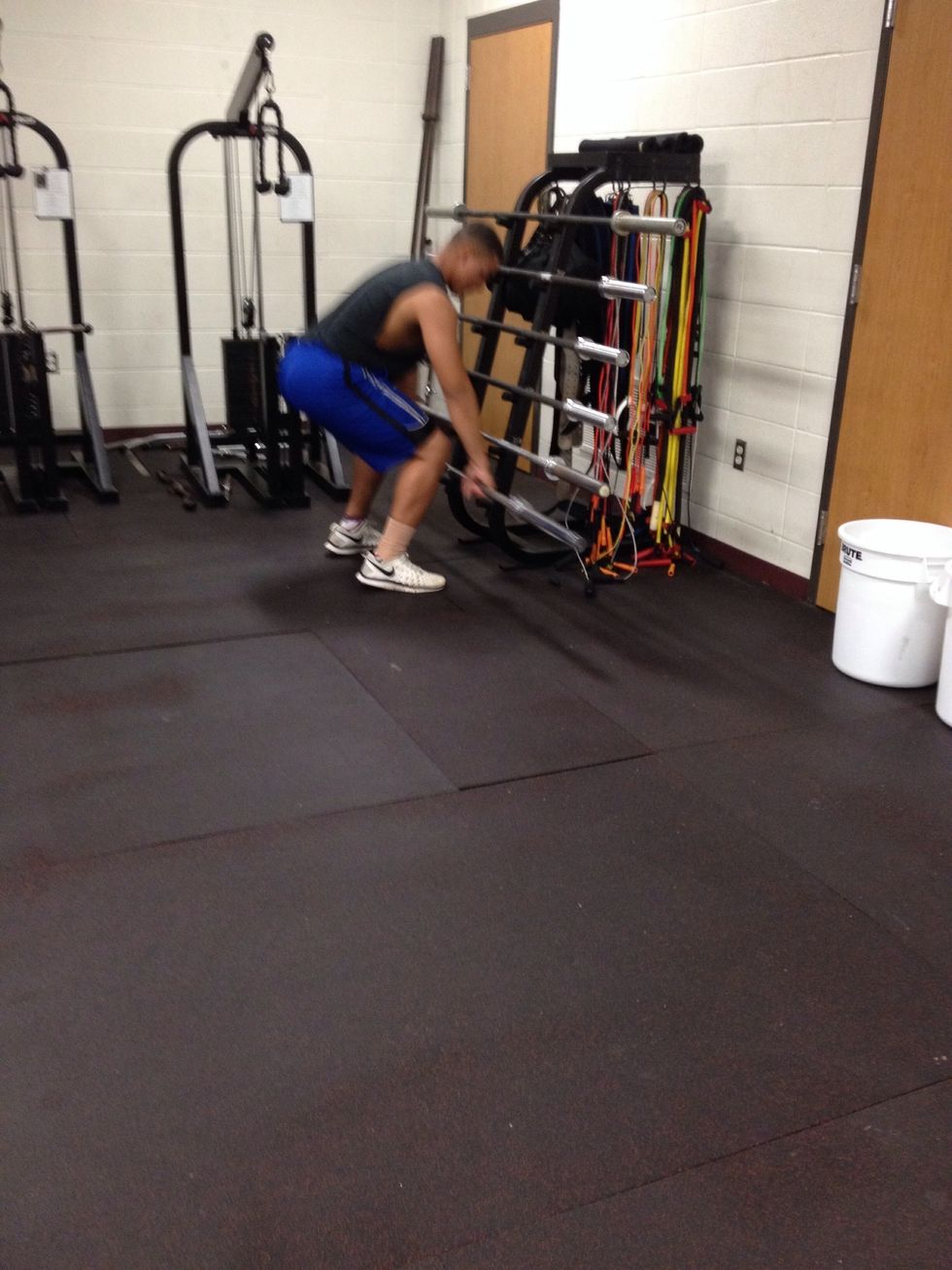 Pick up 45 pound weight lifting bar from rack.