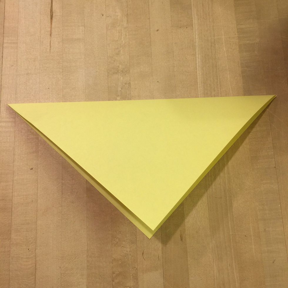 Pick up a corner and match it to a diagonal corner so that it creates a triangle.