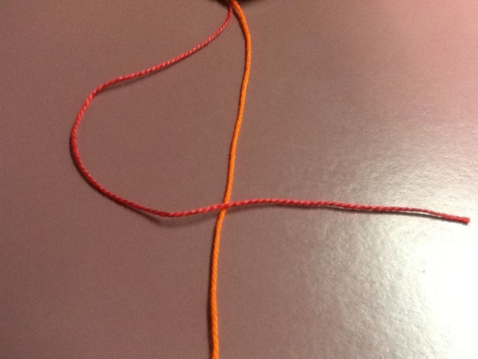 Pick up the first string on the left (red), and place it over the string beside it (orange).