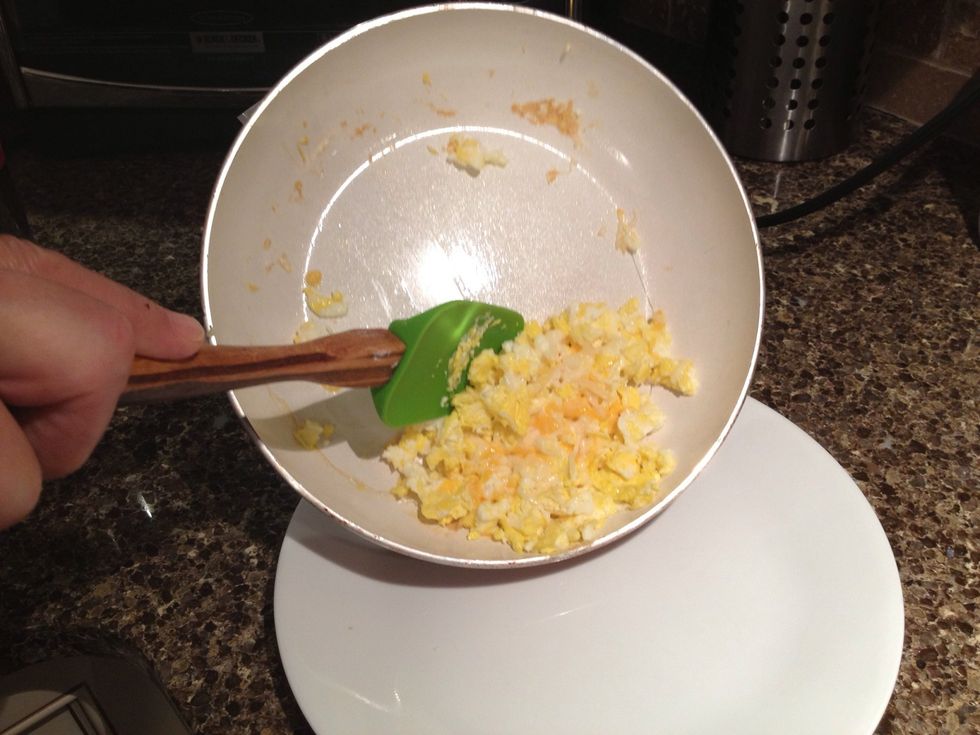 Pick up the pan by its handle and use the spatula to put the scrambled eggs on the plate