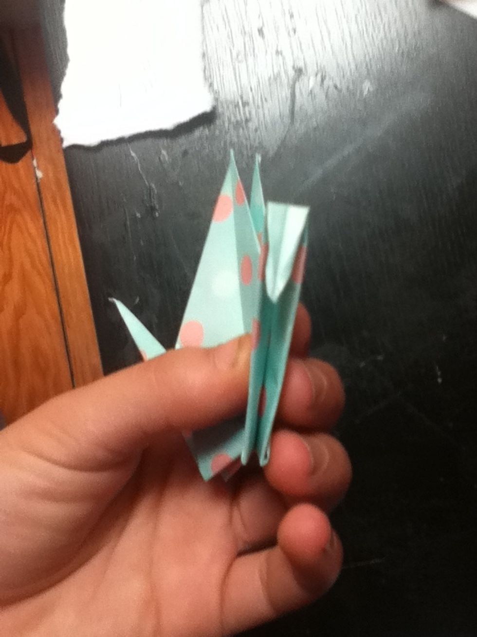 Pick up your crane and fold the top of one of the thin strips in on itself. Tuck it in so it lays flat against the strip that it's part of.
