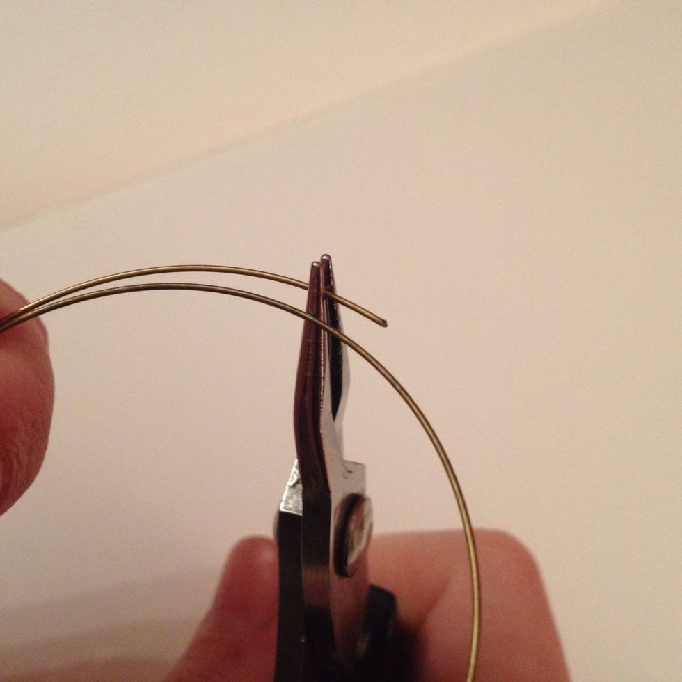 Pick up your memory wire bracelet, grip one end with your round nose pliers approximately 8-10mm from the edge and bend it back to a slight angle.