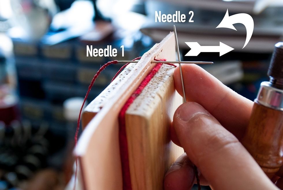 Pierce the next hole using your awl and push the left needle (needle 1) through while holding the needle 2 behind it. In the next step you will hold both needles in your right hand.