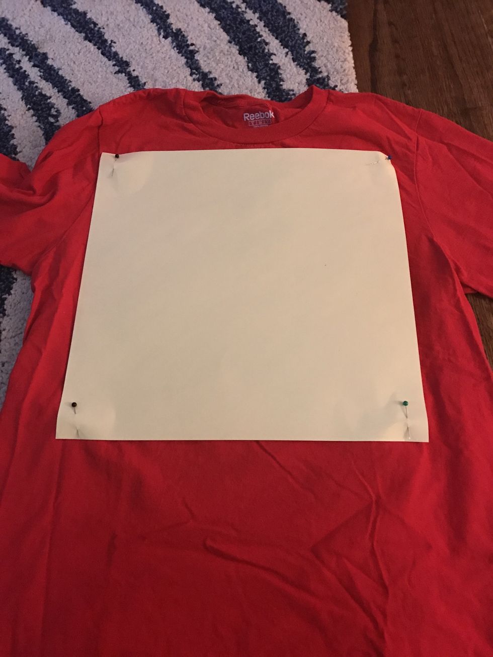 Pin paper in place. It is very important that your shirt remain flat! Any wrinkles will cause uneven squares and it will be difficult to sew them together later on.