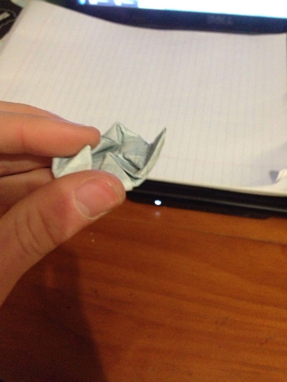 Pinch the slightly folded corner down and pull the underside up so it's almost inside put. This is difficult to explain and do but the photos might help...