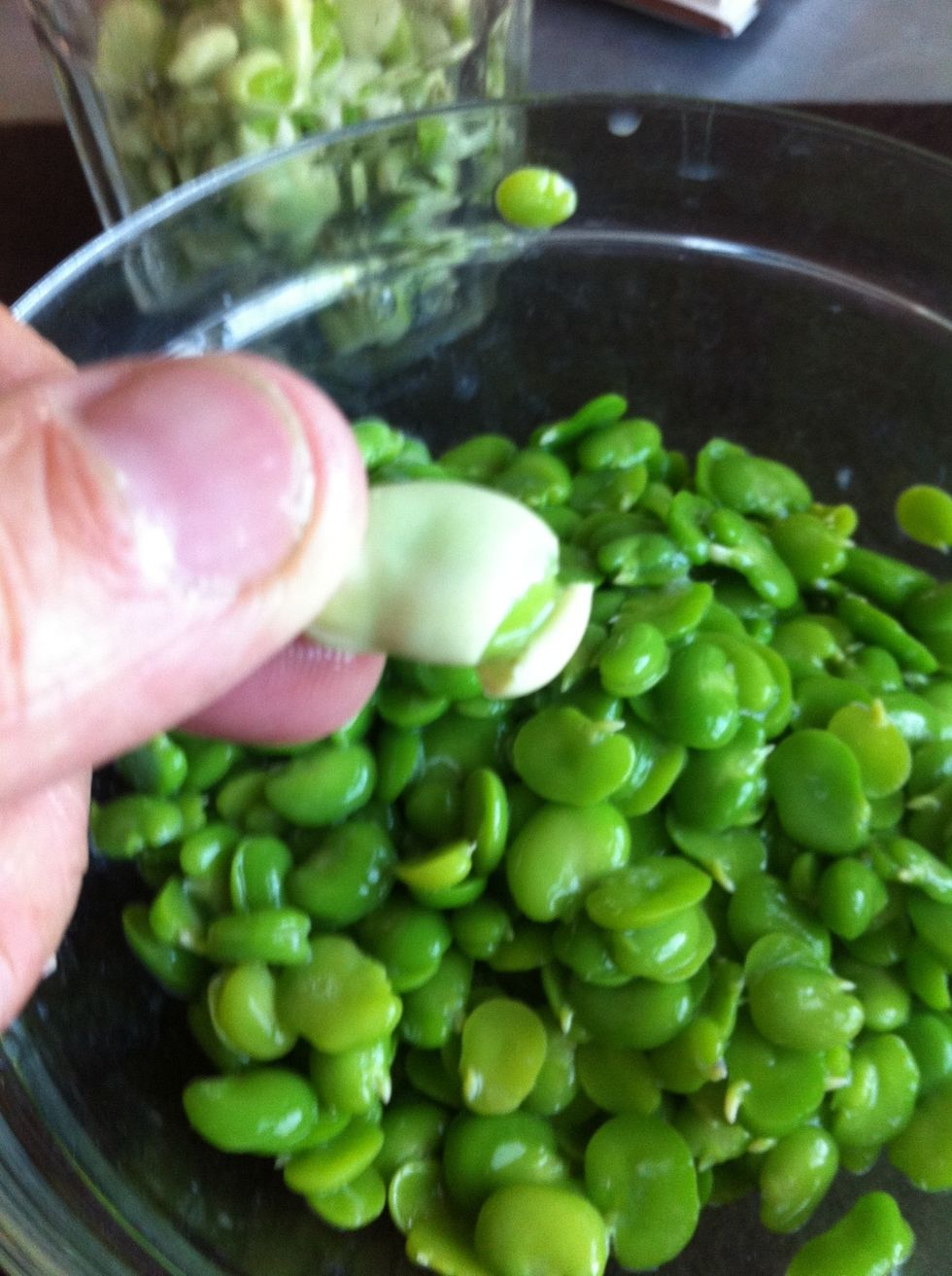 Pinch the tip of the bean. Tear it with your fingernail or twist the skin open then squeeze out the bright green beans into the bowl.