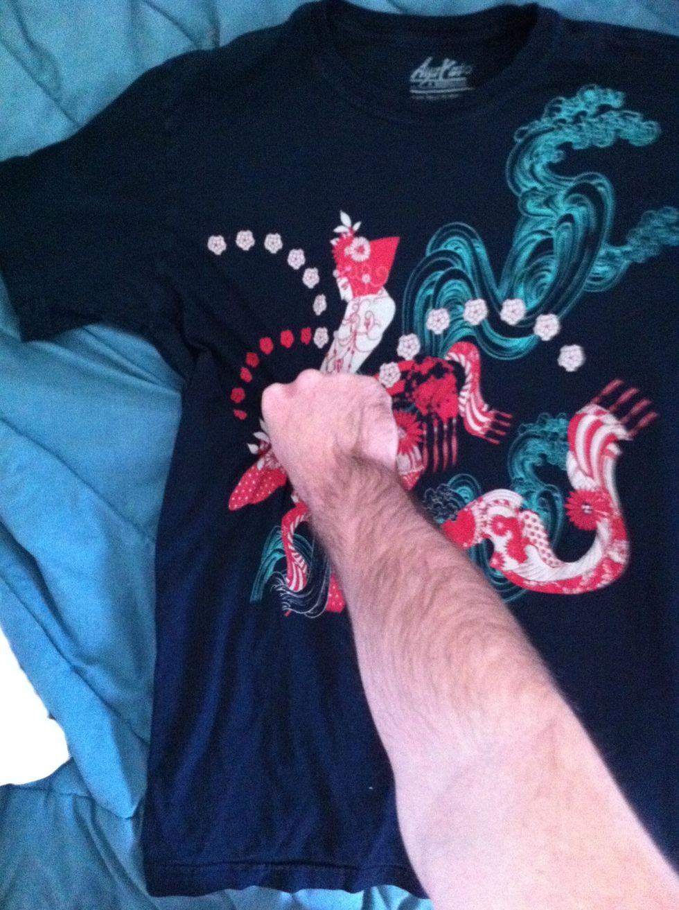Pinch your t-shirt with your right hand. About halfway down, even with the left edge of the left collar. Make sure to pinch the front and back layers of the fabric.
