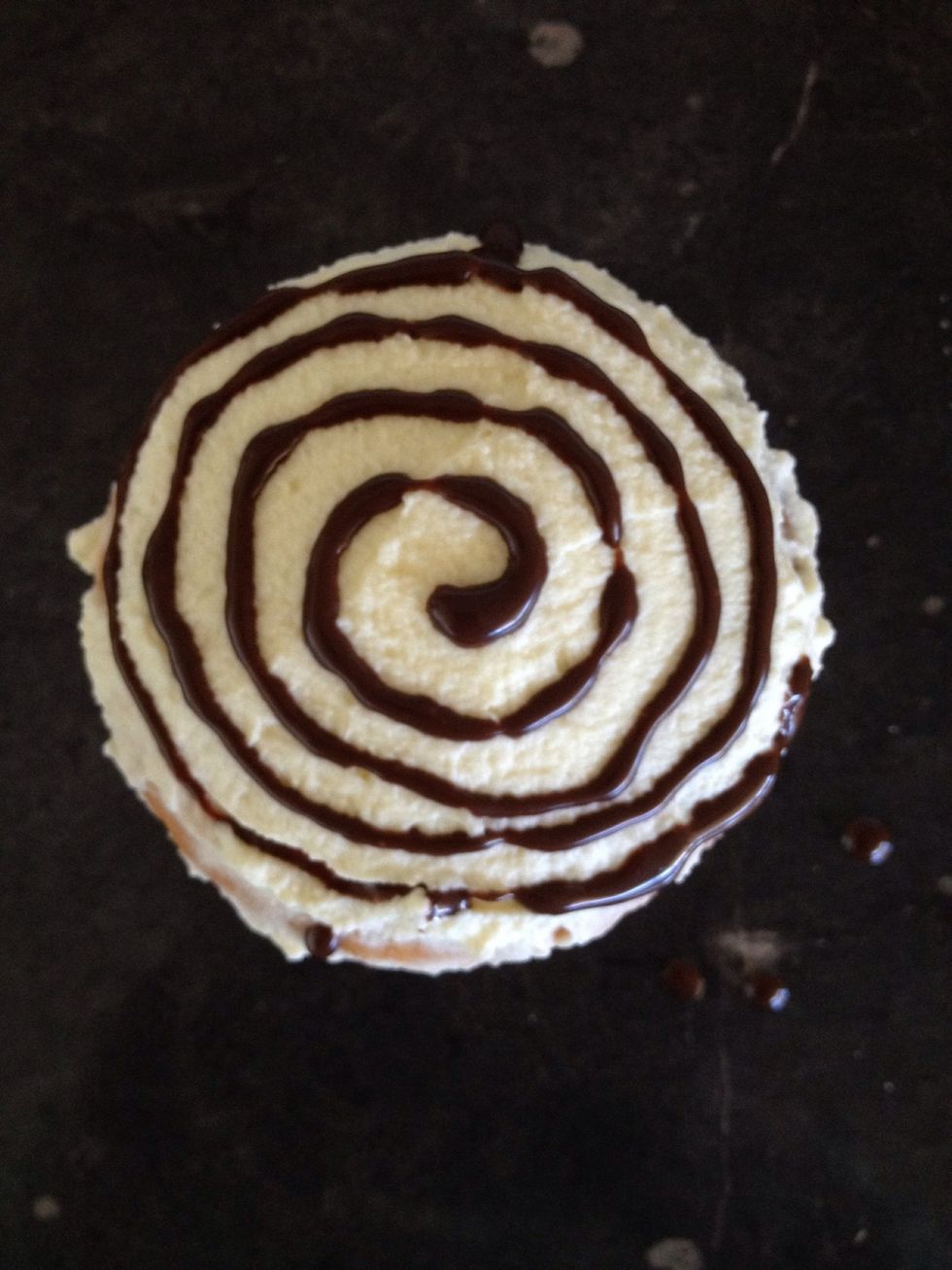 Pipe a swirl pattern with the chocolate syrup on another iced cupcake.