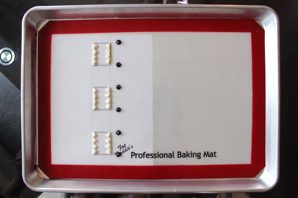 Pipe in the black eyes. Freeze the design for 5-10 minutes. It doesn't need to be rock hard but it shouldn't be runny either. The firmer the frosted design, the better for layering different colours.