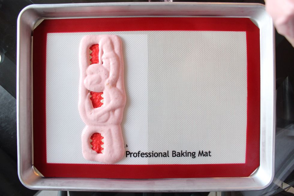 Pipe (or spoon) about 1 cup of your cake batter over the design using a sandwich bag with a corner snipped off.  Start with piping around the eyes first. Then pipe around the mouth.