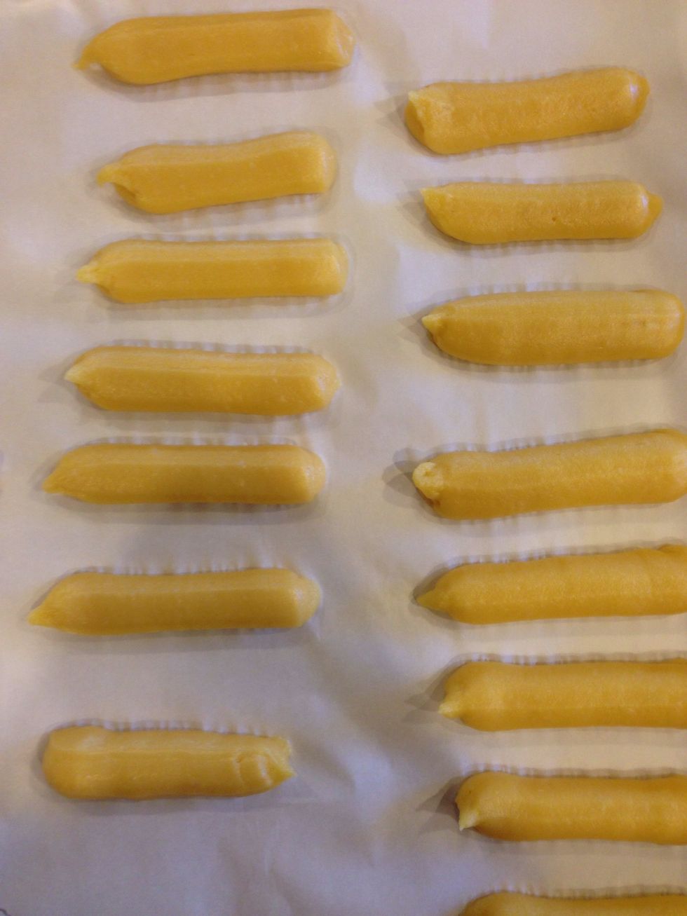 Pipe out 3 to 4 inch long pieces of dough on a parchment lined baking sheet.