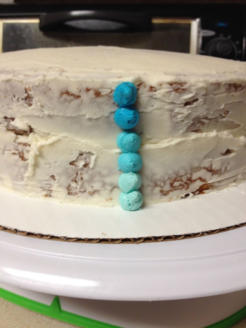 Pipe two dots of each color, starting with the lightest color, in a straight line up the cake