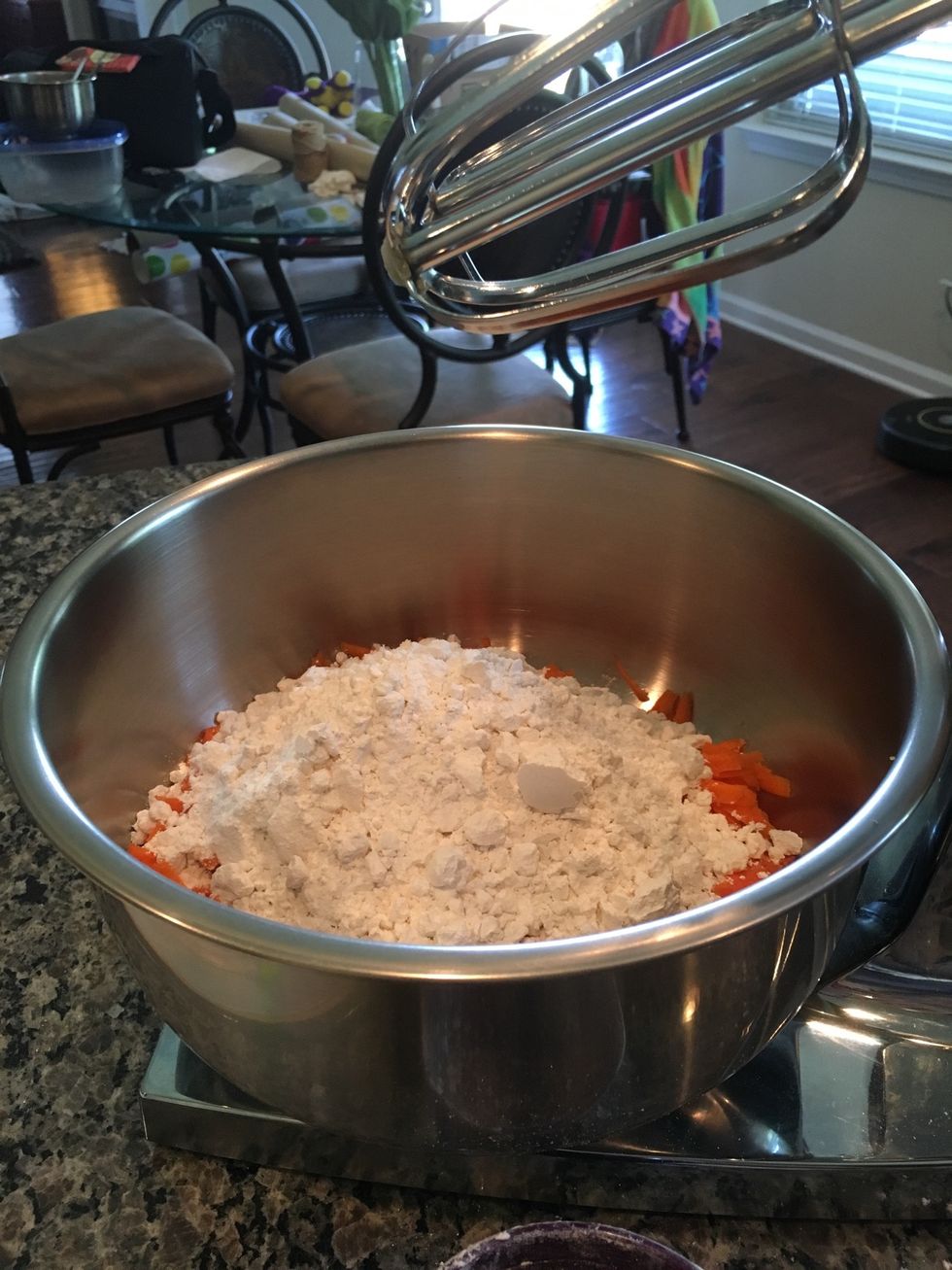 Place 2 cups of all-purpose flour into the mixing bowl with the grated carrots.