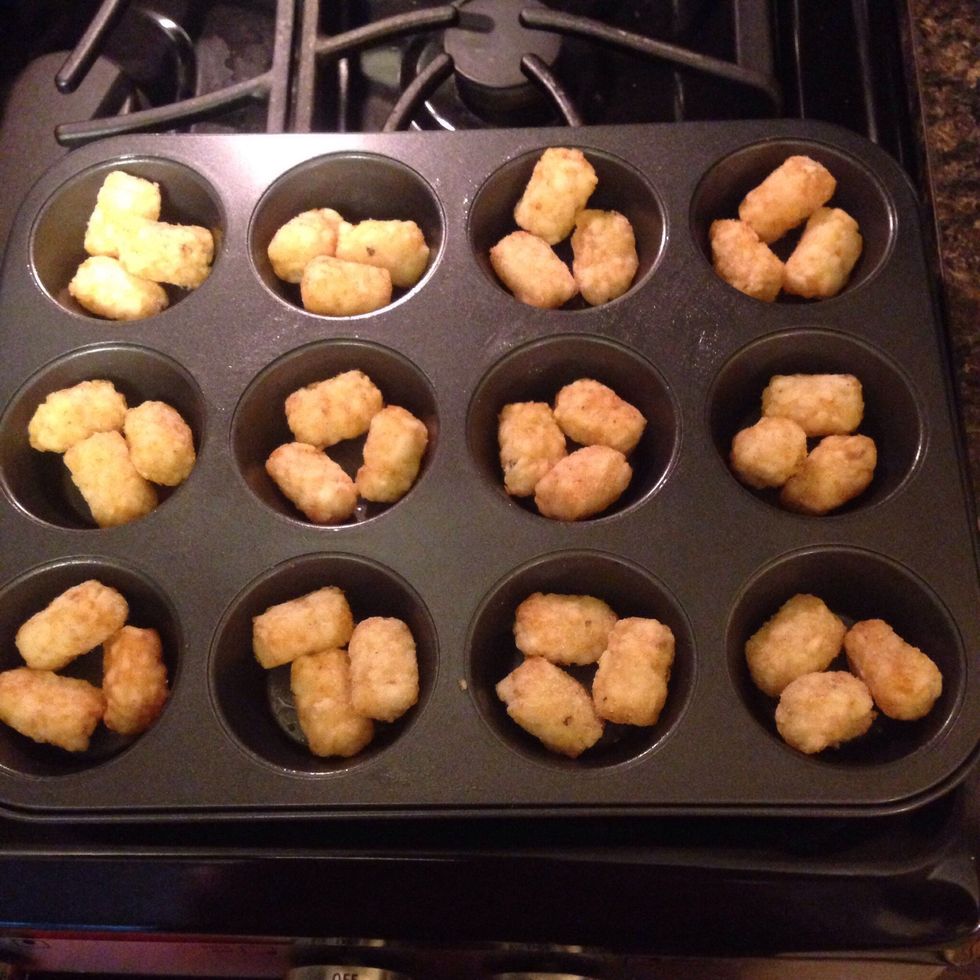 Place 3 frozen tater tots in bottom of each muffin tin and bake for 10 minutes at 400 degrees.