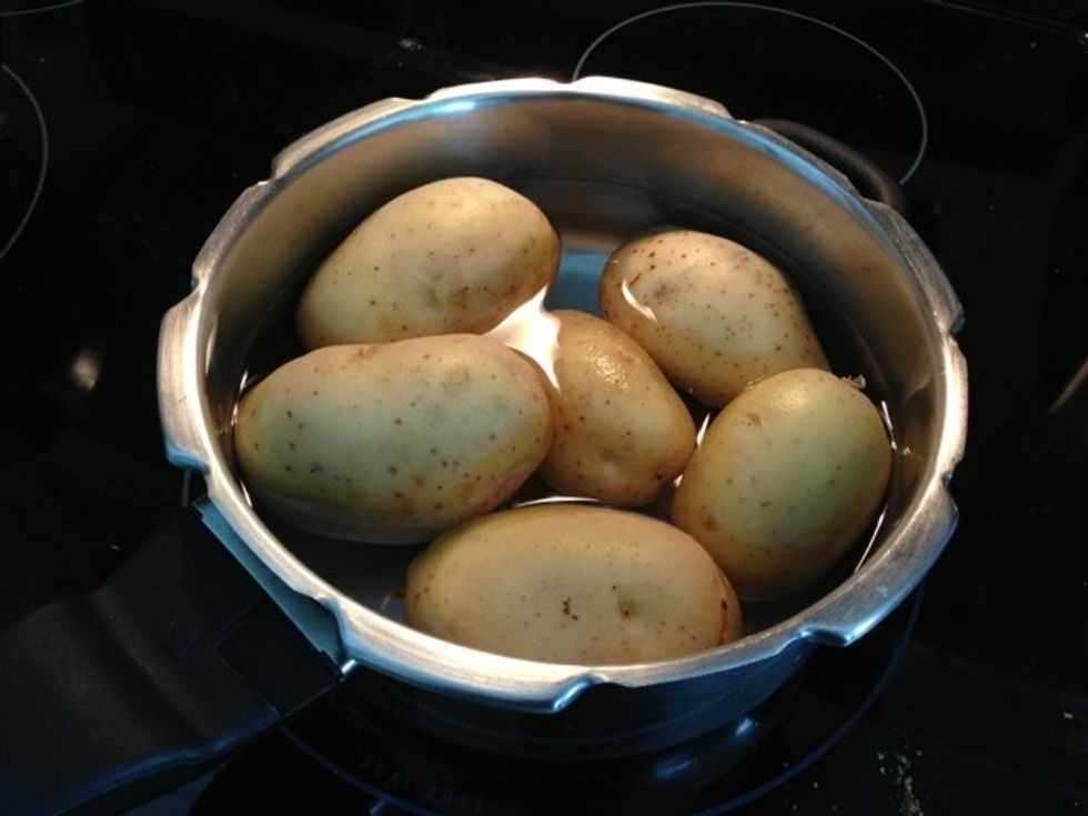 Place 5-6 Yukon gold potatoes in the pressure cooker and fill it with water. Let the potatoes dip more than half in water. There should be little enough water so that there is no overflow