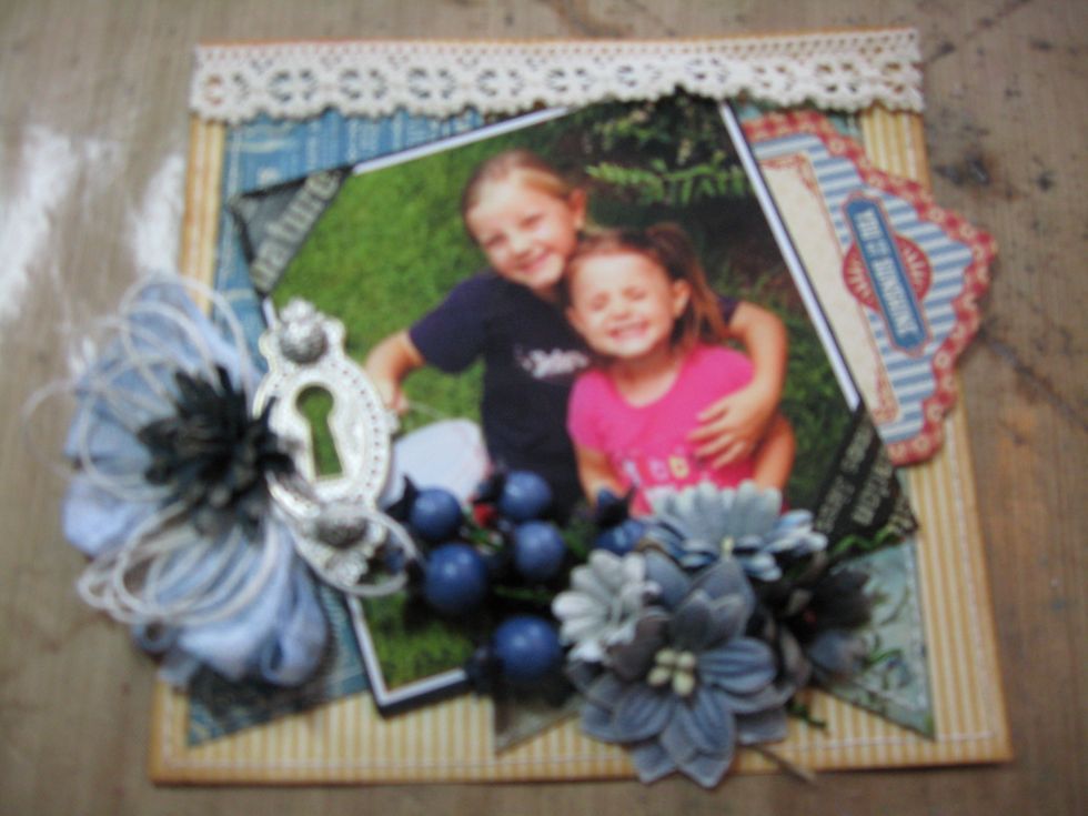Place a dab of hot glue beneath the ornate keyhole. Use the tips of your scissors to poke the ribbon into the hot glue. Top with Ivory Burlap String Bow and a flower.