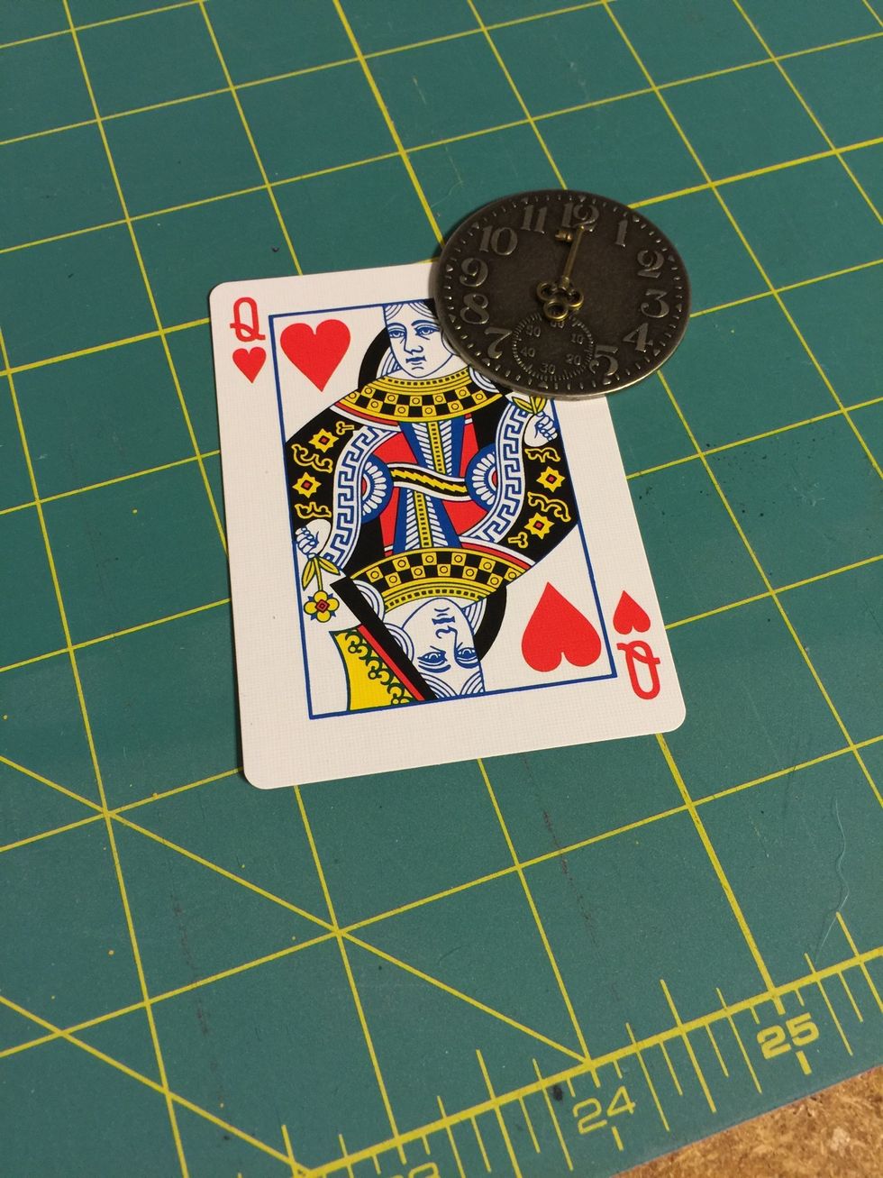 Place a dot of super glue on the top right hand corner of playing card and position clock.
