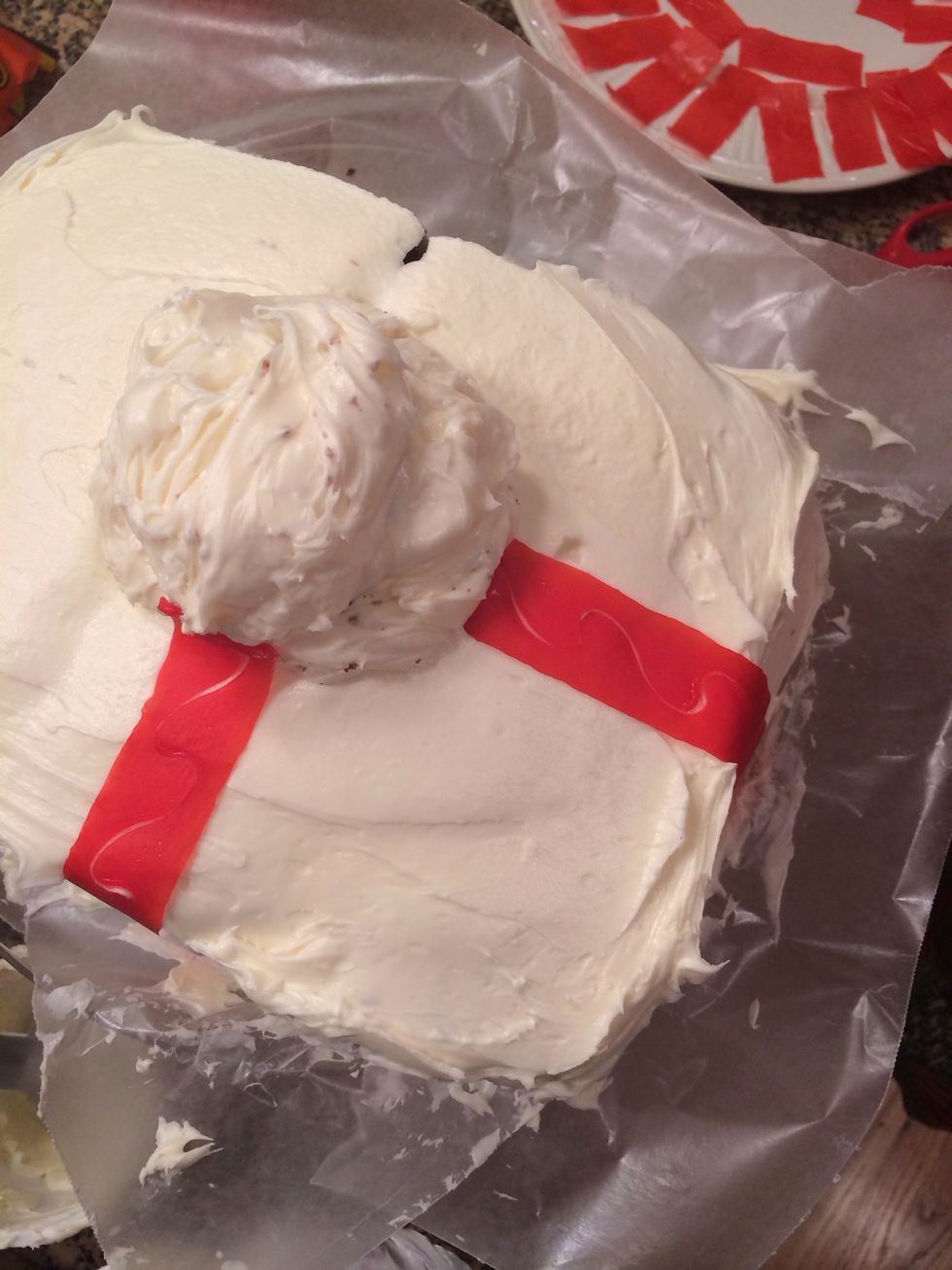 Place a heaping dollop of frosting onto the middle of the cake. Then, lay Fruit Rollup strips coming in a cross shape from the middle (like a present). Snip at ends, when the Rollup reaches the plate.