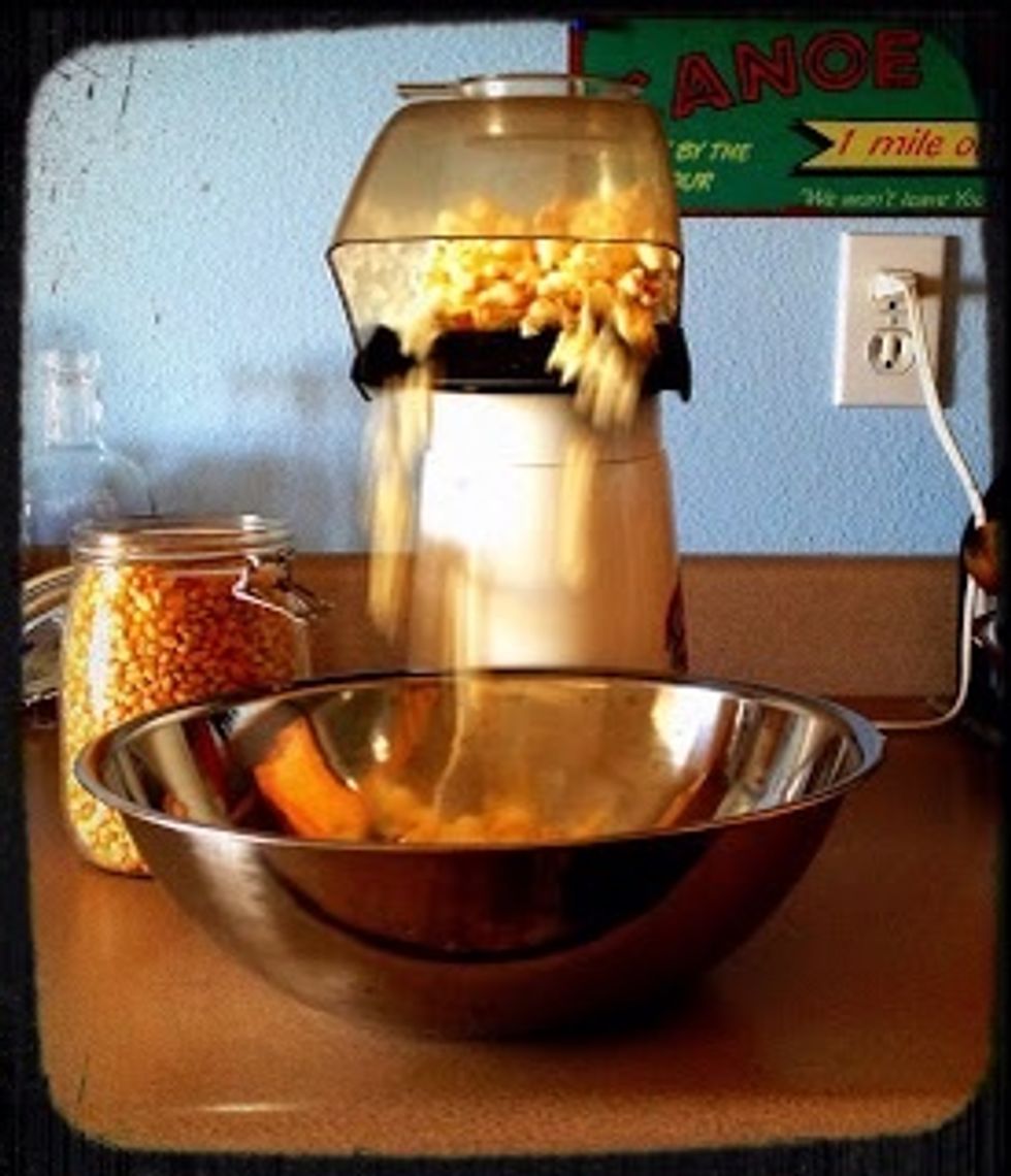 Place a large bowl at the spout of your popcorn maker.
