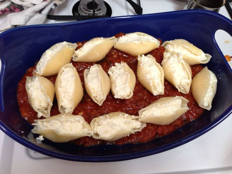 Place a layer of your finished sauce in a baking dish. Then place the stuffed shells in a layer on top of the sauce.