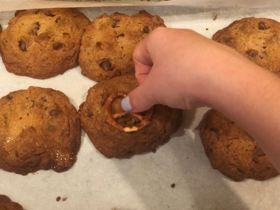 Place a pretzel in the middle of each cookie while warm