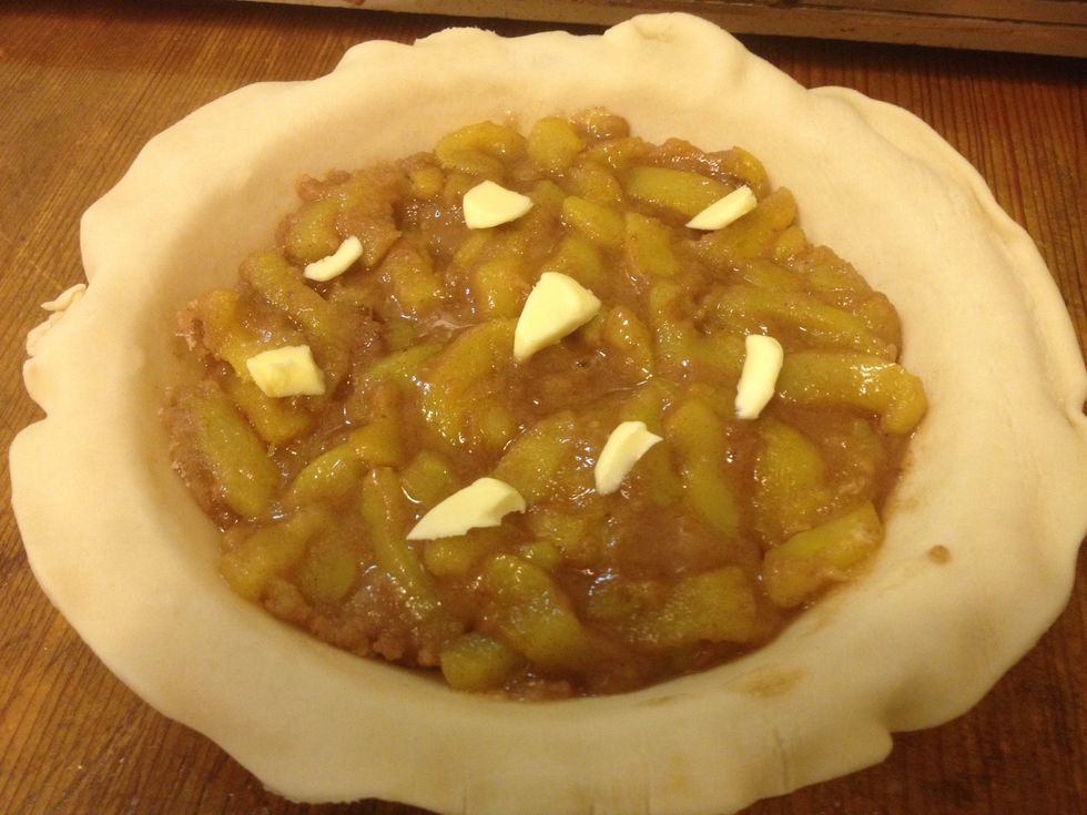 Place a sheet of pie crust in an 8 inch pan. Pour the spiced slices in and spread them out evenly. Dot with butter.