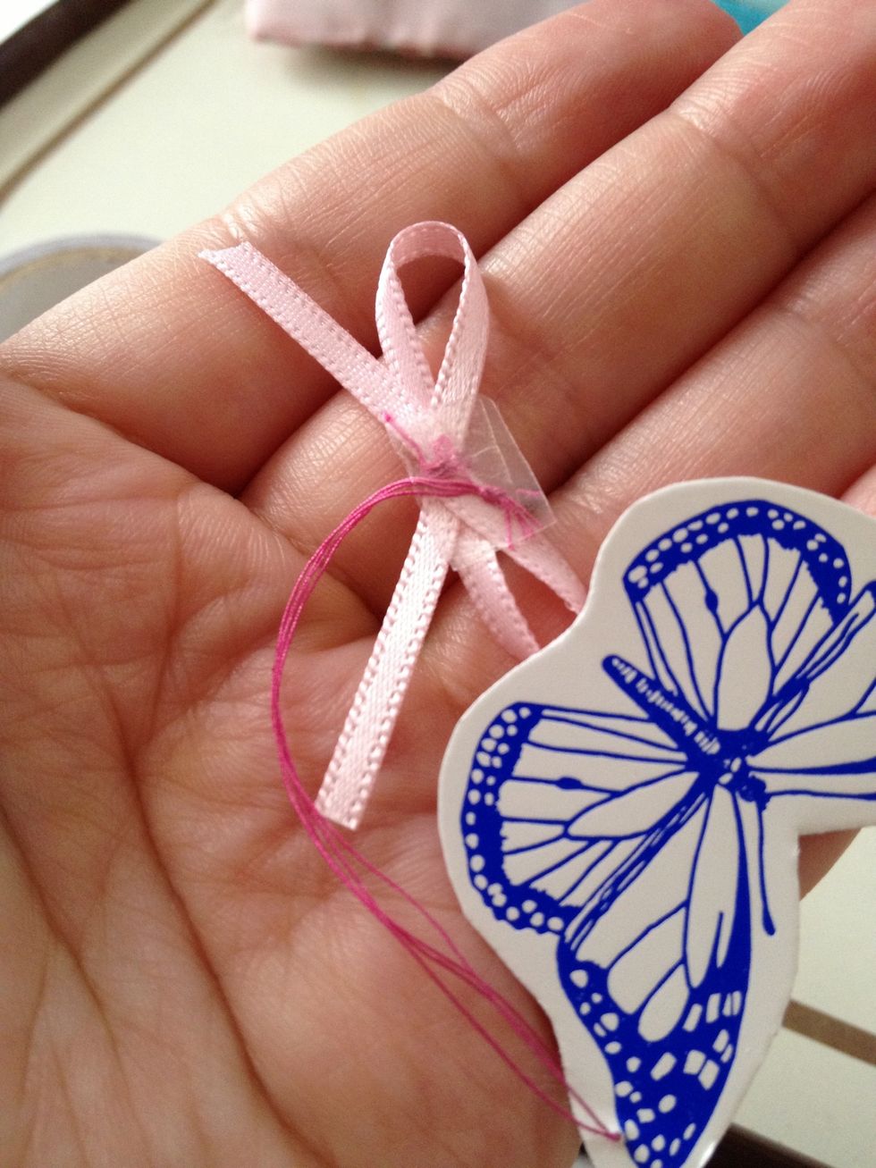 Place a small piece of tape to the now and place card thread on to