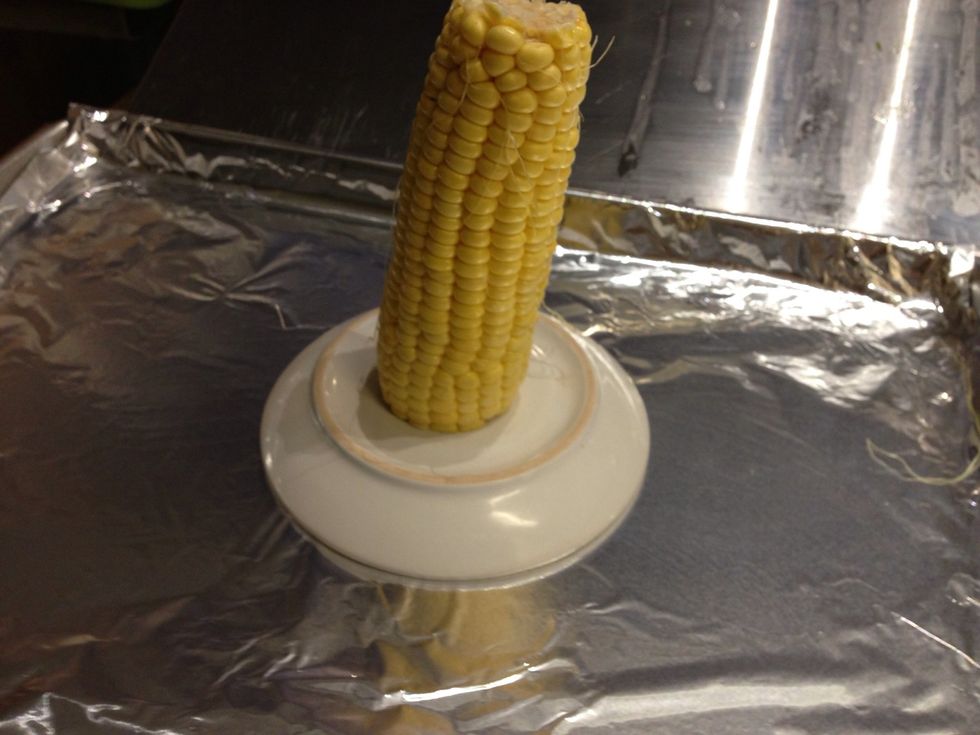 Place a small plate or bowl on top of the foil and place an ear of corn on top to slice off the kernels.