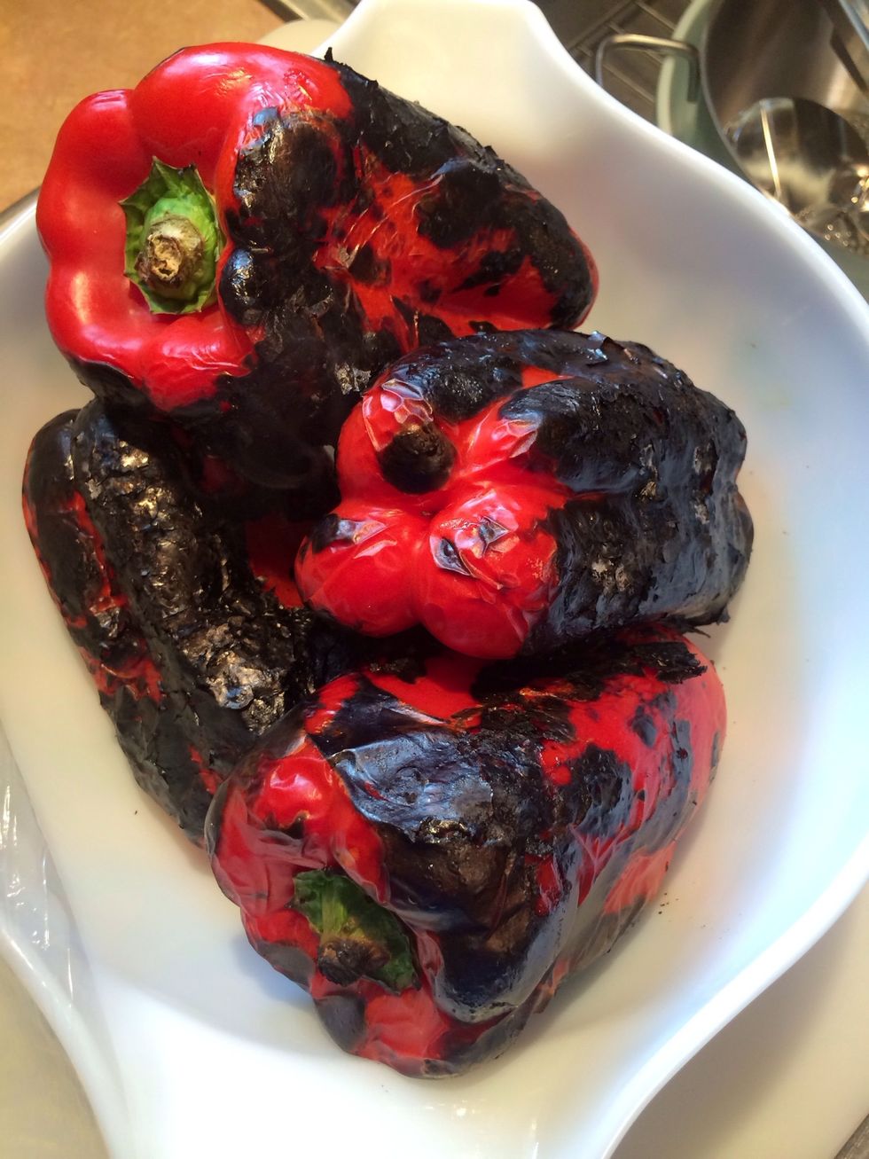 Place all the roasted peppers in a bowl and cover with plastic wrap or dinner plate on top of the bowl and let rest 15 minutes. This allows the pepper to cook, & makes the skins easier to remove.