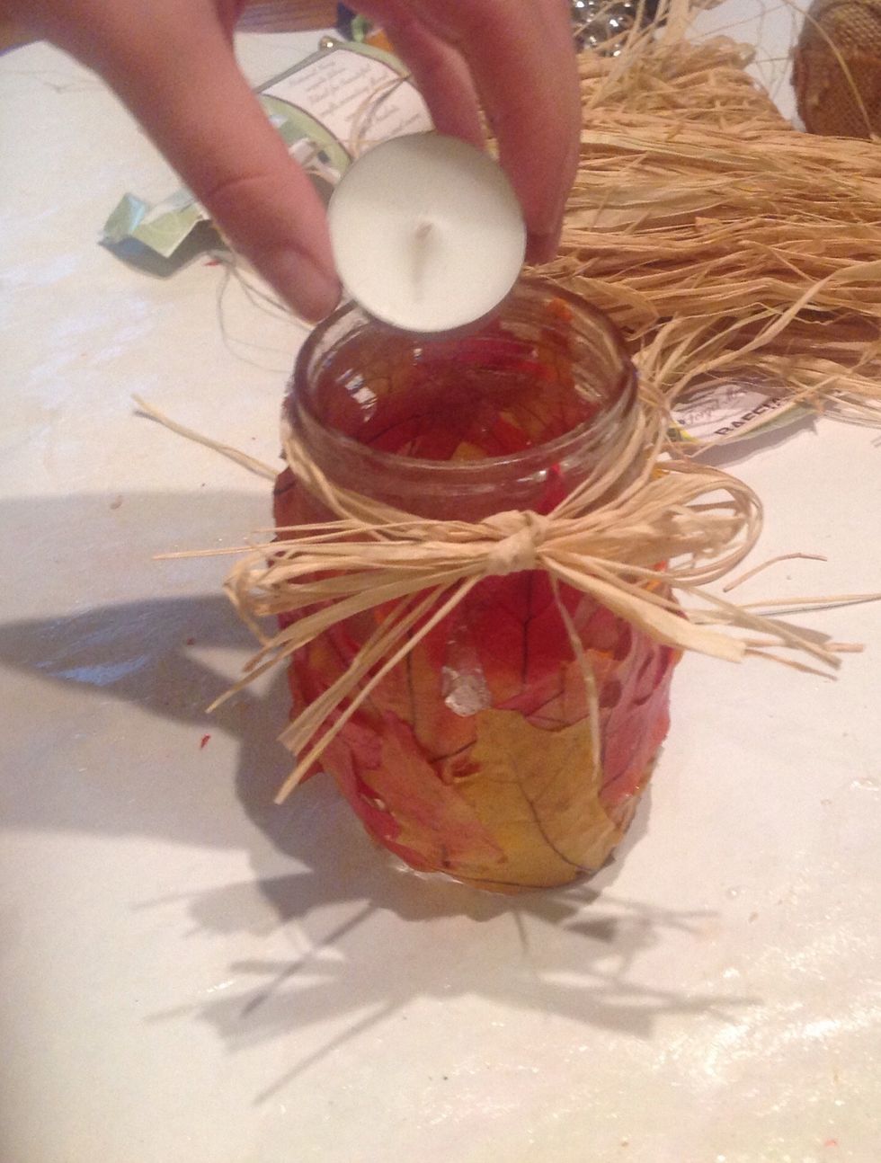 Place an UNLIT tee-light in the bottom of the jar. If you light the tee-light before placing it in the jar the raffia is more likely to catch fire.