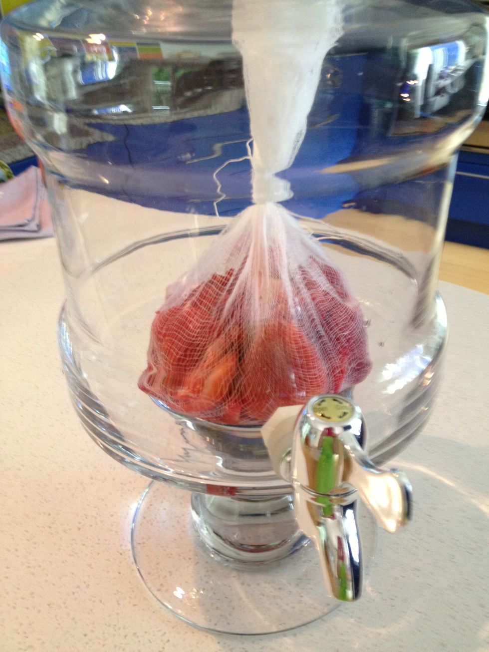 Place berries in glass beverage dispenser.