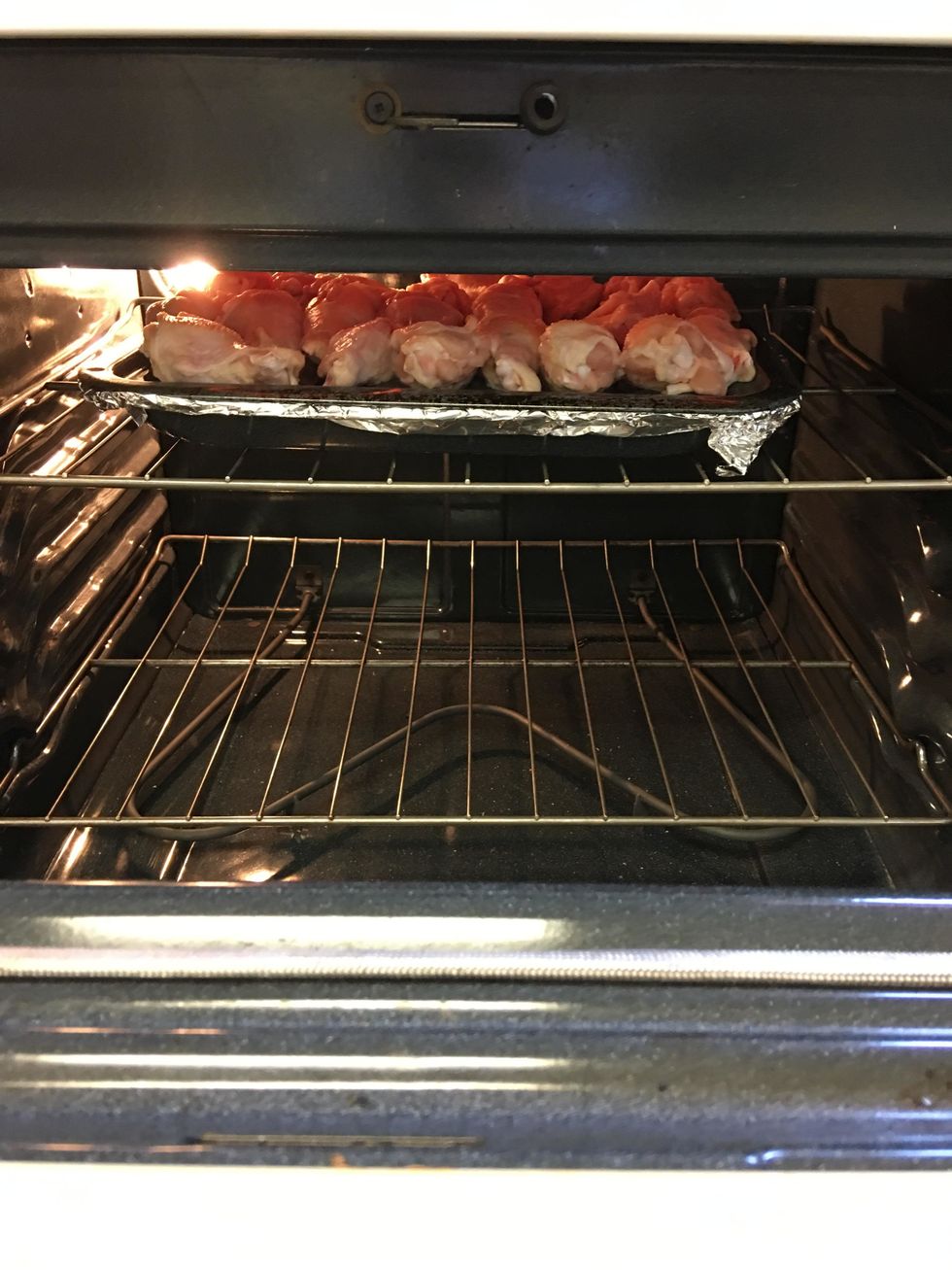 Place broiler pan with chicken wings on top rack within the oven.