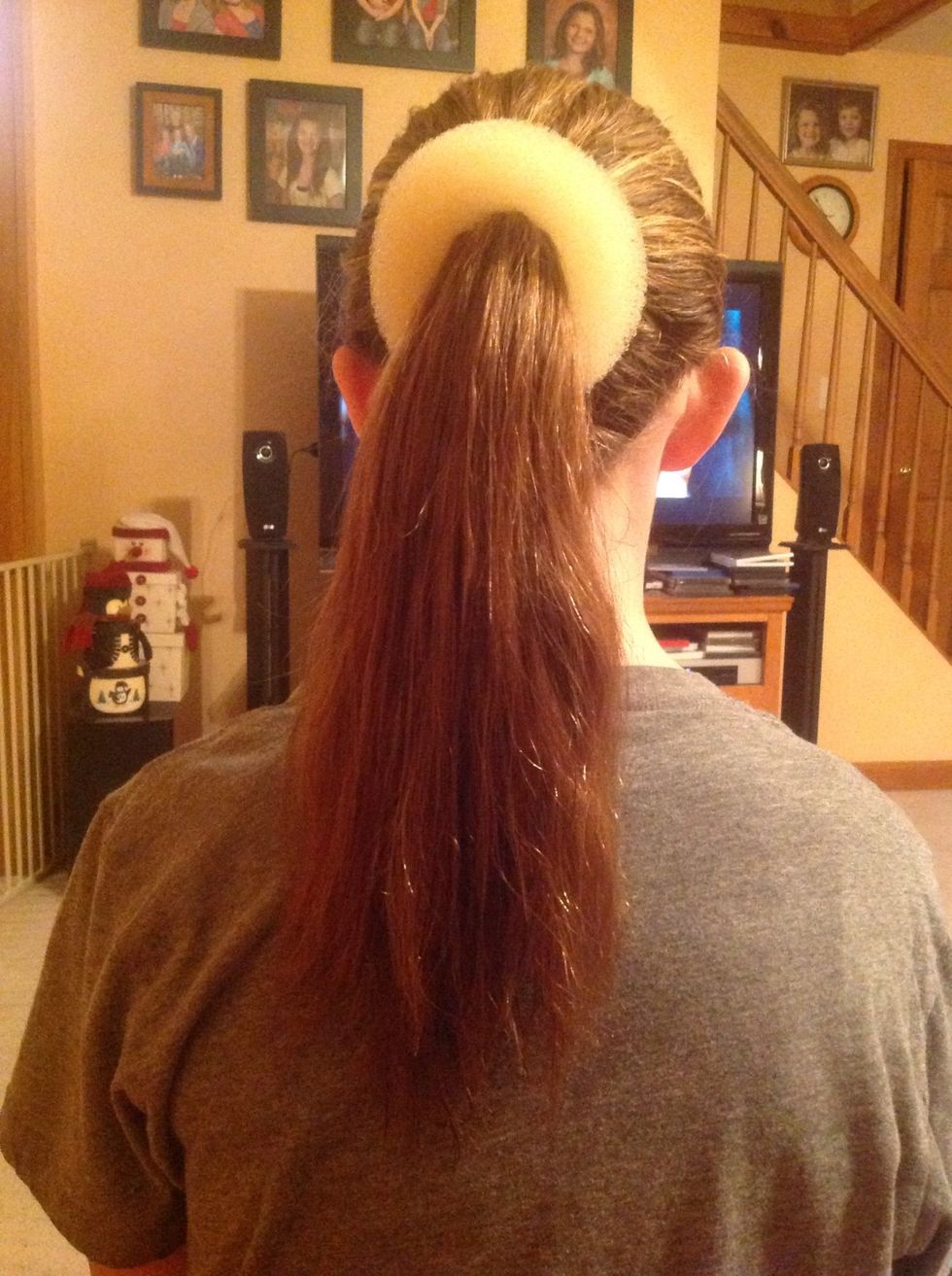 Place "Bun Ease" at the base of the ponytail. If you do not have a "Bun Ease" you can use an old sock with the toes cut off.