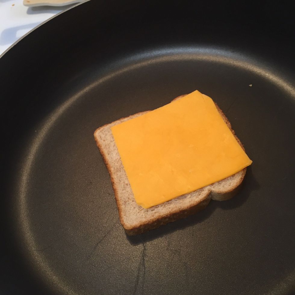 Place buttered bread into your skillet and add cheese slice