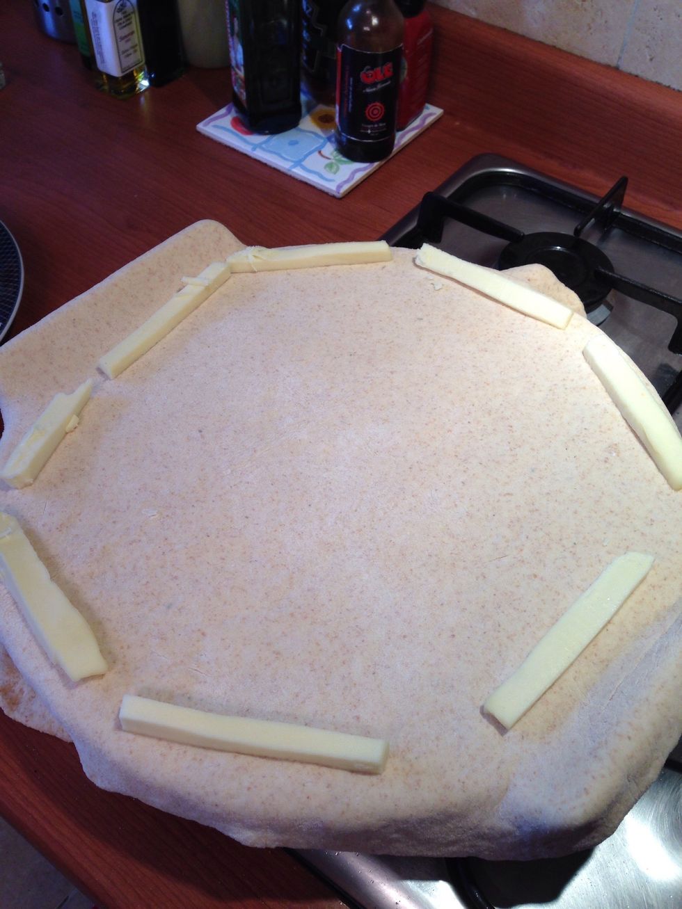 Place cheese sticks around the edge of the pizza