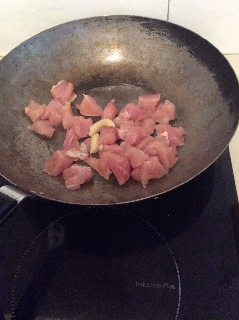 Place chicken in wok with garlic and let it fry.