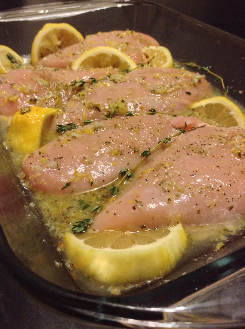 Place chicken into the baking dish and with a spoon pour a little of the lemon and thyme sauce on top of the chicken. Add your lemon wedges and a few sprigs of fresh thyme and your ready for the oven.