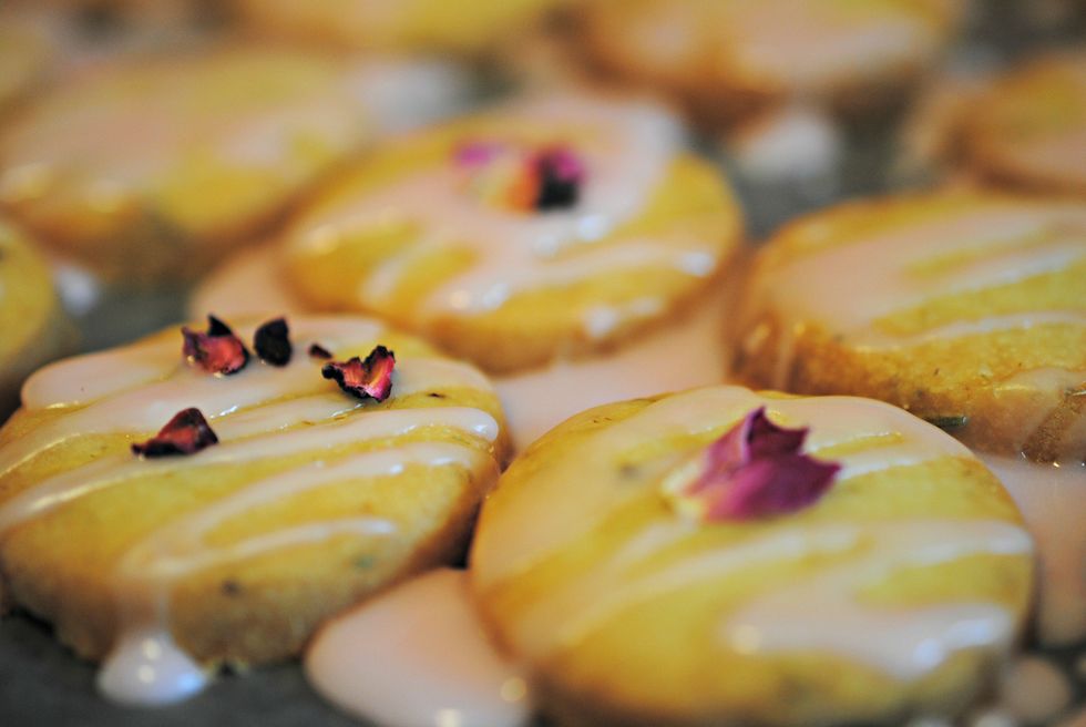 Place cookies on parchment paper and drizzle glaze over them with a fork. Decorate with rose petals.