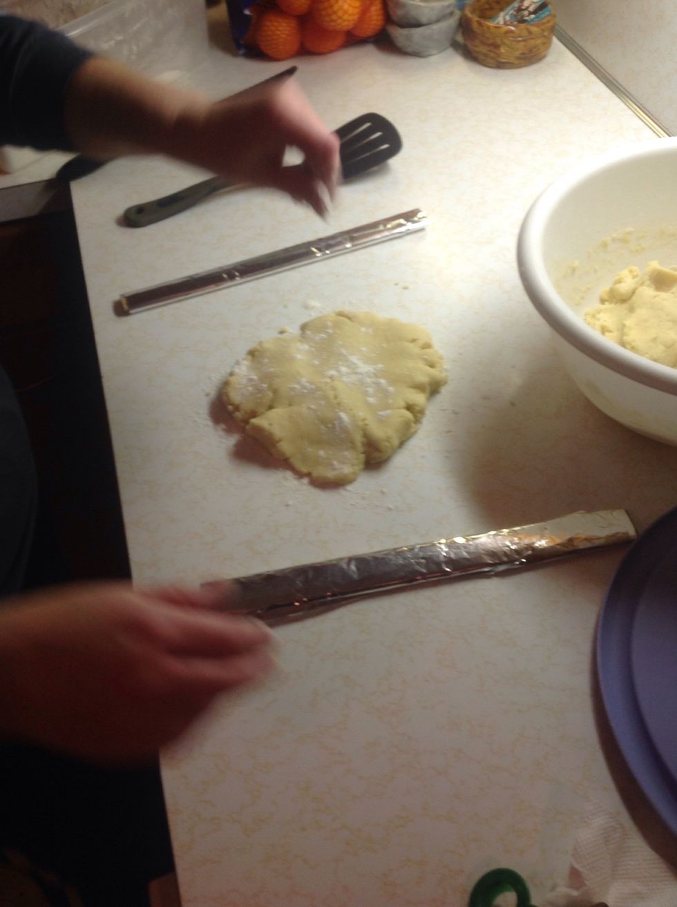 Place dough between the rulers and sprinkle the dough with flour. The extra flour keeps the dough from sticking to the counter or rolling pin.