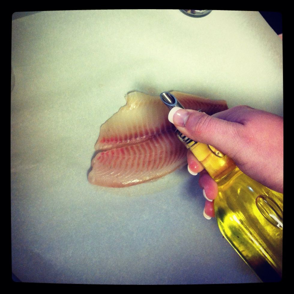 Place fish on the parchment paper and drizzle with oil.