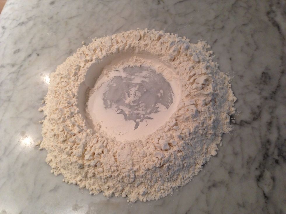 Place flour in a mound on your work surface and create a well, or hole, in the center as shown.