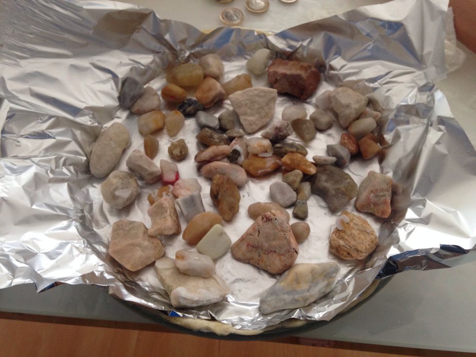 Place grease proof paper over the top and press down and add some old coins to stop the dough from rising.(Today I'm using foil and pebbles) Cook the dough for 15mins at 180c in the middle of the oven