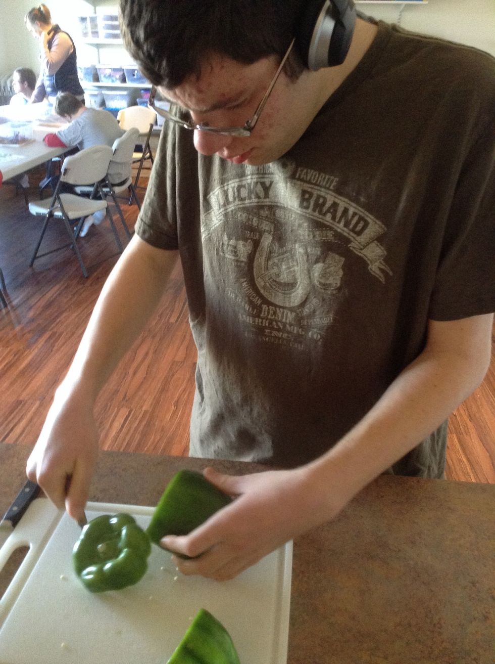 Place green pepper on cutting board then carefully using knife cut the top off. This should get all the seeds out but you may need to pick some seed out of the pepper