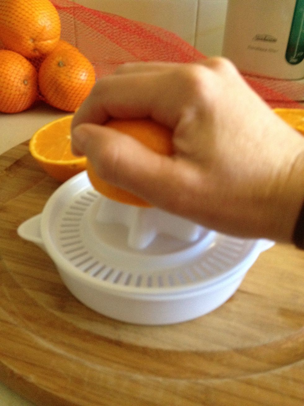 Place half an orange on the juicer then press and turn.