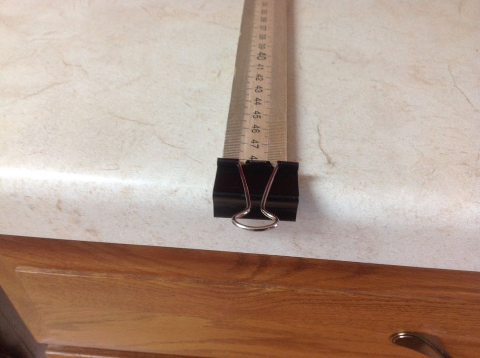 Place half meter stick on a flat surface with the flipped side of the binder clip facing down.
