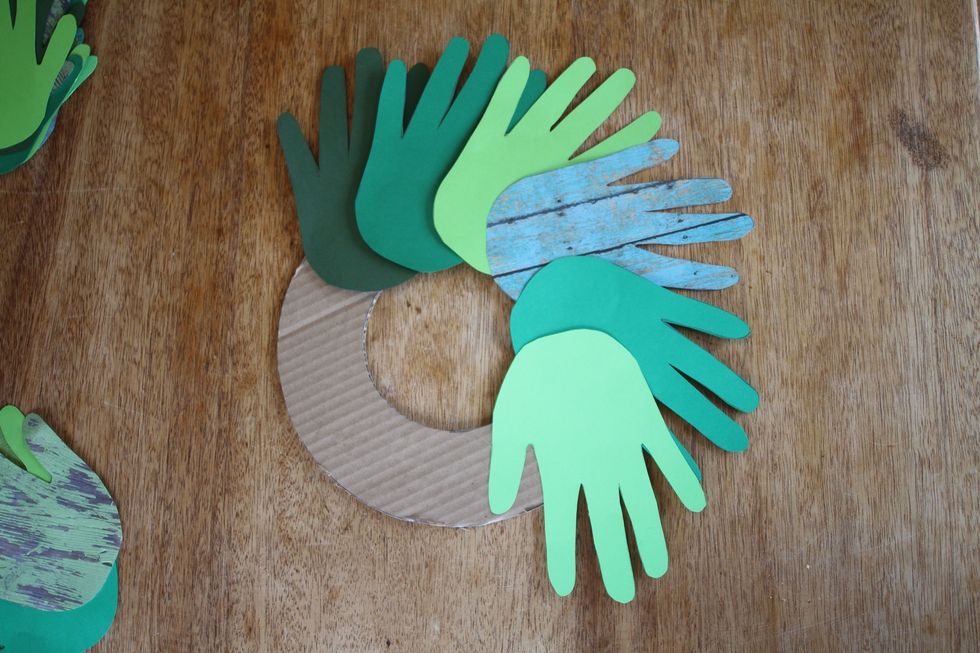Place handprints, one overlapping another, on the doughnut, w/ the heel of the hand covering the cardboard & fingers fanning outward to the edges. You can angle them slightly, or leave them straight.