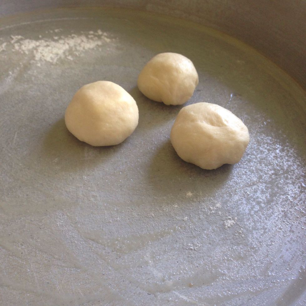 Place it into the prepared pan. Continue with the rest of the dough till you're finished .. And make sure to leave space between the dough balls to allow room for them to rest.
