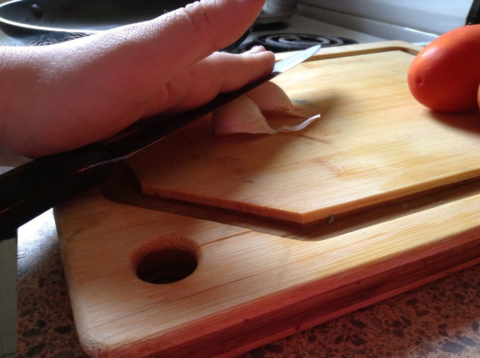 Place knife over garlic (be careful of fingers!); apply pressure to smash garlic