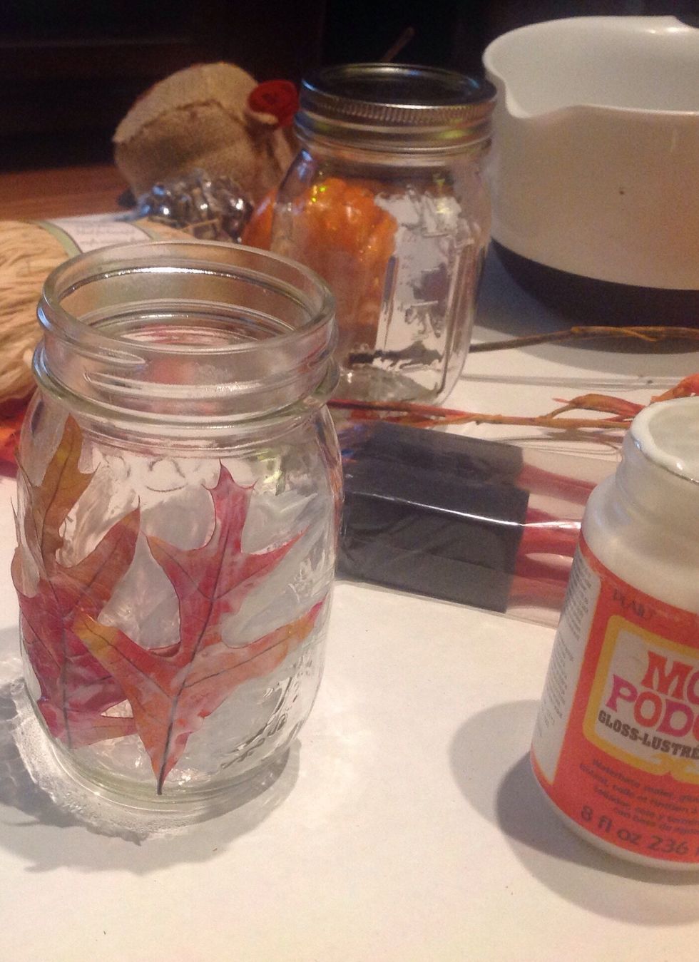 Place leaves where the mod podge has been added to the jar. Once the leaf is in place paint over it with a coat of Mod Podge.