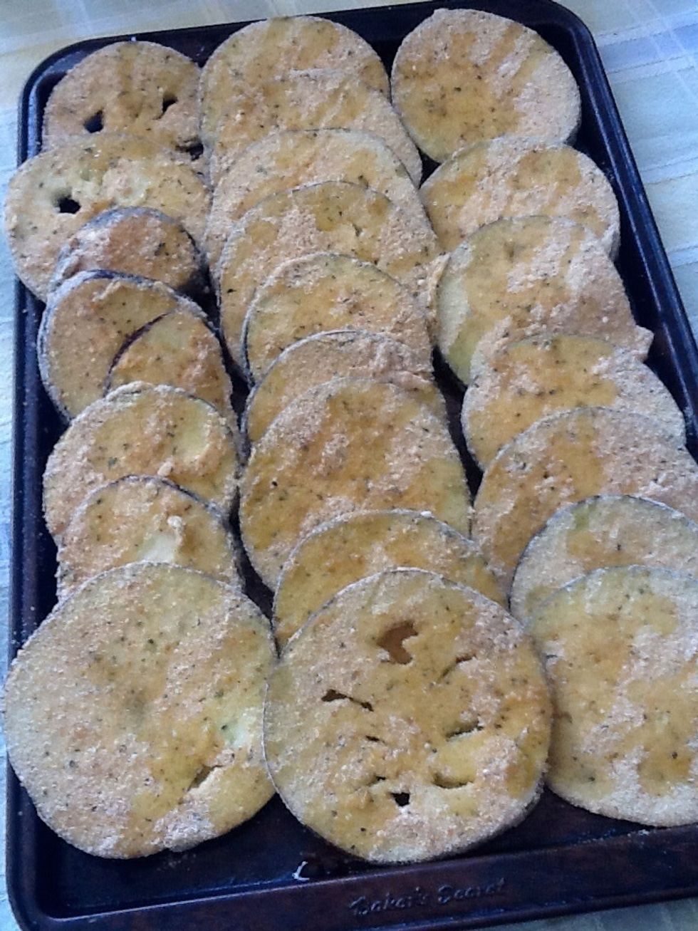 Place olive oil on baking sheet to prevent sticking and to add flavor !  Place single layers of breaded eggplant slices on to baking sheet, a bit of overlap is fine.